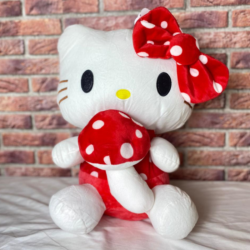 Plush toy hello kitty a character with a red bow and polka dot dress against a brick wall.