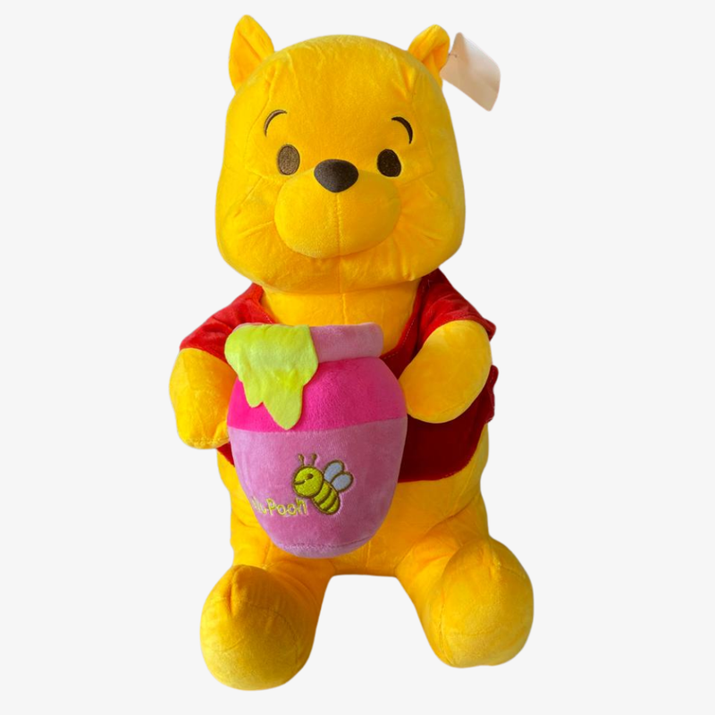 Plush toy of a bear weiny the pooh holding a honey pot on a white background